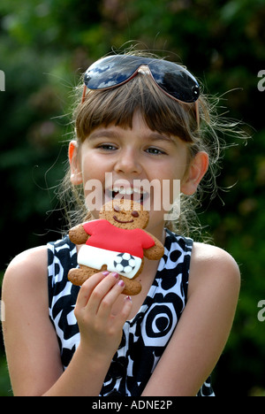 Young girl eating Market Drayton gingerbread man, Shropshire, England, UK Stock Photo