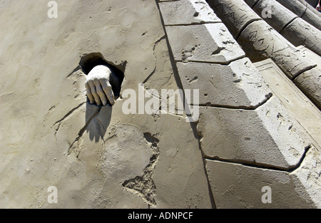 A spooky sand hand coming out of a tomb sculpted in sand at Black Rock on Brighton Beach Stock Photo