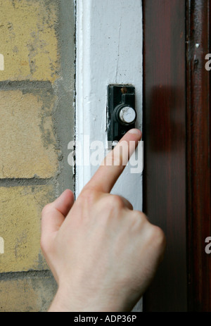 mans hand pressing finger to old black doorbell calling household Stock Photo