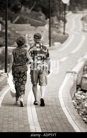 Senior couple walking away together along footpath Life lifestyle elderly age old people Stock Photo