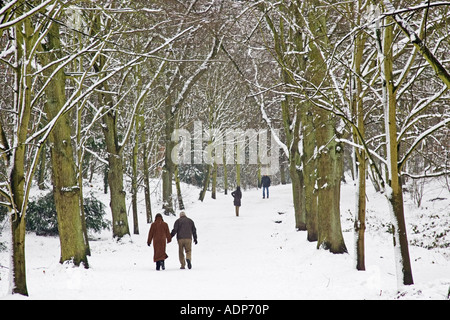 Couple walk hand in hand across snow covered Hampstead Heath North London United Kingdom Stock Photo