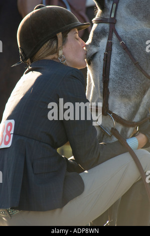 A tender moment during lull in action between teen girl and her horse at show jumping event Stock Photo