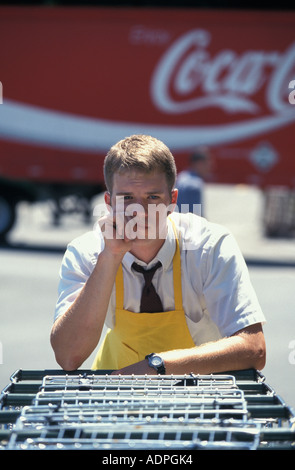 Portrait of hot and tired Caucasian teenage grocery store clerk collecting shopping carts Stock Photo