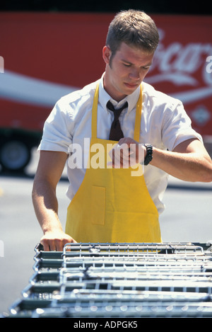 Portrait Caucasian teenage grocery clerk collecting shopping carts near quitting time Stock Photo