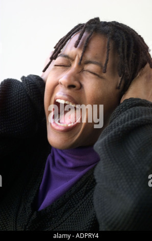 Black Woman Yelling and Covering Ears Stock Photo
