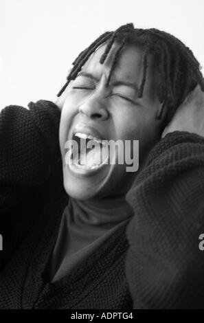 Black Woman Yelling and Covering Ears Stock Photo