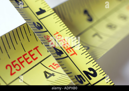 Yellow metal tape measure against a white background, inches, centimetres, feet, metres Stock Photo