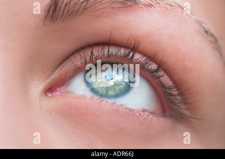 Extreme close up of womans eye looking up blue sky reflecting in eye Stock Photo