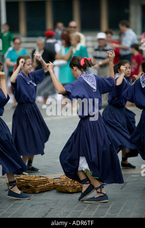 Young Basque girls dressed in blue perform a traditional Basque folk dance around baskets Plaza Arriaga Bilbao Stock Photo