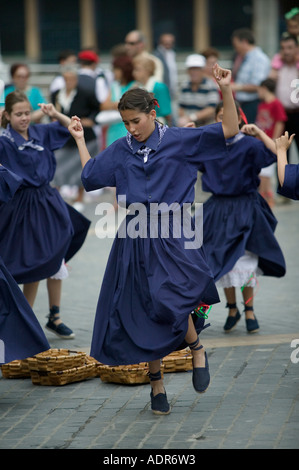 Young Basque girls dressed in blue perform a traditional Basque folk dance around baskets Plaza Arriaga Bilbao Stock Photo