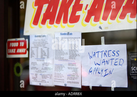 wattress wanted apply in hand written misspelt waitress sign in window of take away cafe and take away sign and price list Stock Photo