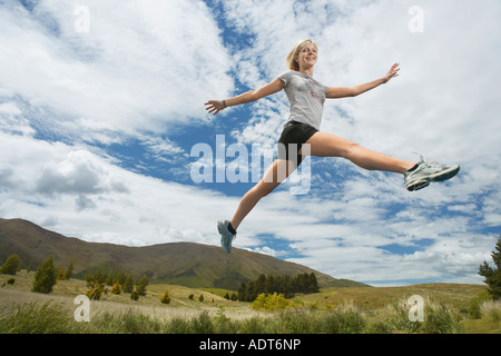 Woman leaping in hills Stock Photo
