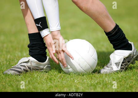teenage boy demonstrates traditional way of picking the football up from the ground during gaelic football game Stock Photo