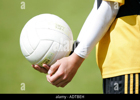 teenage boy demonstrates traditional way of hand passing the football during gaelic football game Stock Photo