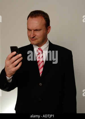 Man in suit looking at mobile - perplexed Stock Photo