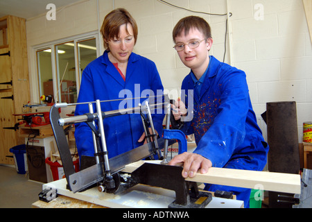 A young man with Downs Syndrome learns how to use saw at a workshop for craftspeople with learning disabilities Ripon North York Stock Photo