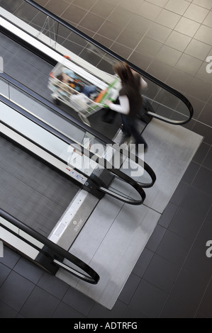 woman pushing trolley on an escalator Stock Photo