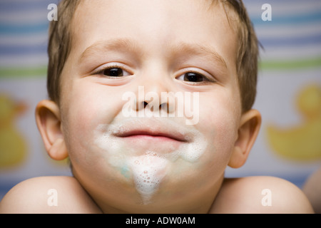 Boy smiling with toothpaste on face Stock Photo