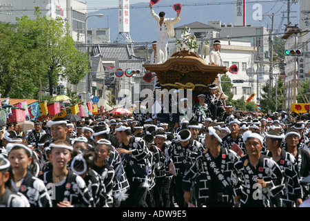 A carpenter dancers wildly and dangerously as his wooden festival float is pulled at high speed through Kishiwada city Japan Stock Photo