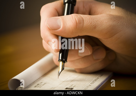 Detailed view of man holding fountain pen and endorsing check Stock Photo