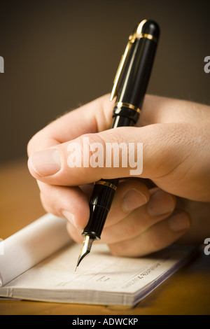 Detailed view of man holding fountain pen and endorsing check Stock Photo