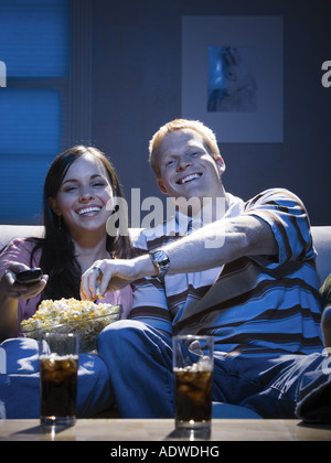 Couple with bowl of popcorn watching television smiling Stock Photo
