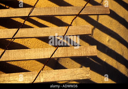 Broken beach fence posts caught in early morning light creates shadows on golden sand Elbow Beach Bermuda Stock Photo