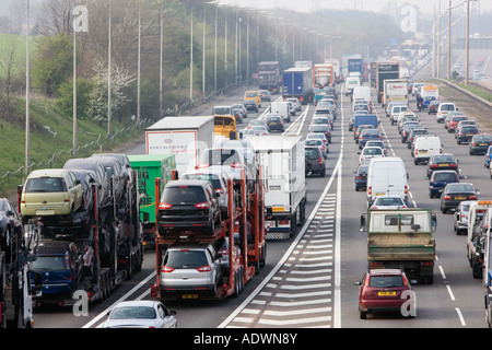 Car transporter lorries travelling among congested traffic on M1 motorway in Hertfordshire United Kingdom Stock Photo