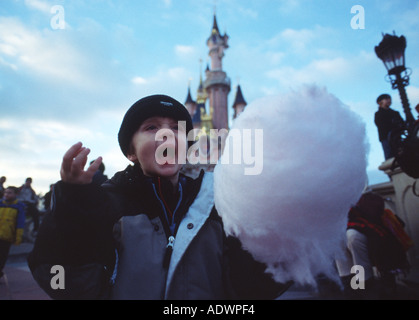 small boy in coat eating candyfloss in winter at the park Stock Photo