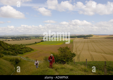Ramblers walk the footpath overlooking a crop circle in Vale of Pewsey Wiltshire England United Kingdom Stock Photo