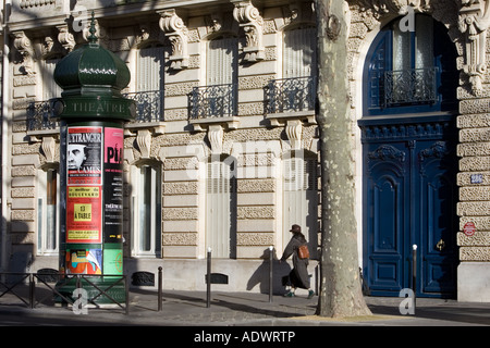 Woman walks past obelisk advertising theatre productions in Parisian street Boulevard St Germain Latin Quarter France Stock Photo