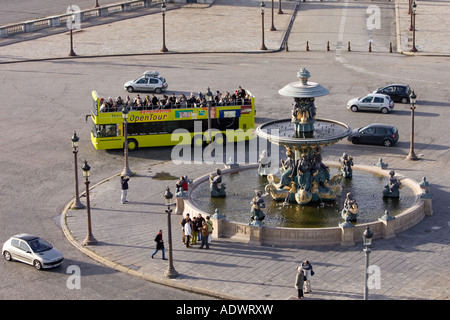 Open air tour bus with tourists passes fountain in Place de la Concorde Central Paris France Stock Photo