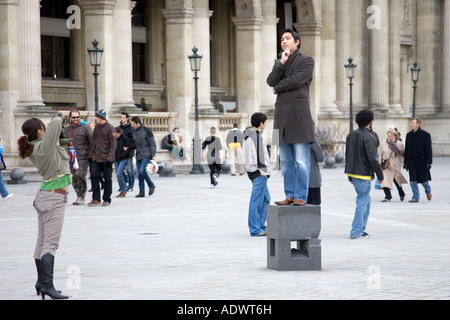 Tourist has his photograph taken balancing on posing plinth outside the Louvre Museum Paris France Stock Photo