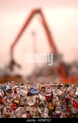 A MECHANICAL DIGGER TOWERS OVER CRUSHED TIN CANS IN BALES AT A METAL RECYCLING FACILITY Stock Photo