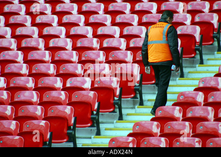 Rows of seats in a soccer rugby football stadium with a steward Stock Photo