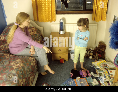 Mother telling off her child in her messy bedroom Stock Photo