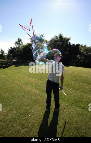 Man in mid twenty's blowing large bubbles outside using a bubble wand. Stock Photo