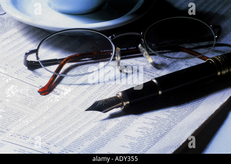 Business Concepts I finance newspaper financial section glasses ink pen saucer economy economics analysis commerce trade busines Stock Photo