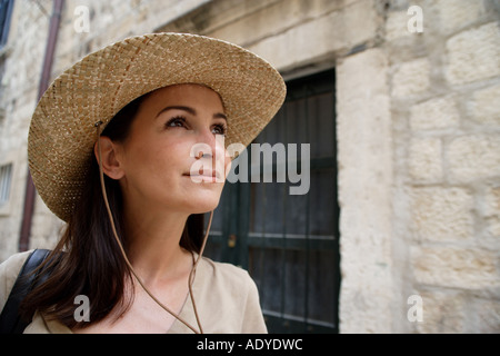 brunette young woman with straw head in front of ancient stonework Stock Photo
