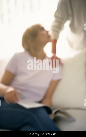 Young woman looking up at unseen male with hand on her shoulder Stock Photo