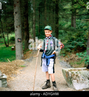 Full length portrait of one boy scout in uniform with badges on sleeve standing outdoors on a woodland trail in Powys rural Wales UK   KATHY DEWITT Stock Photo