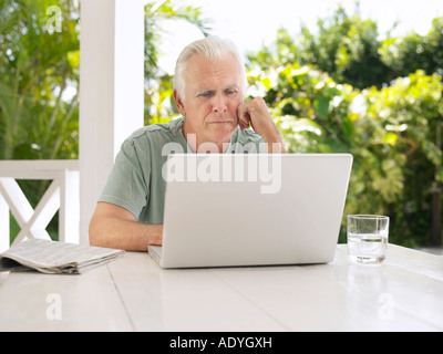 Man using laptop at verandah table Stock Photo