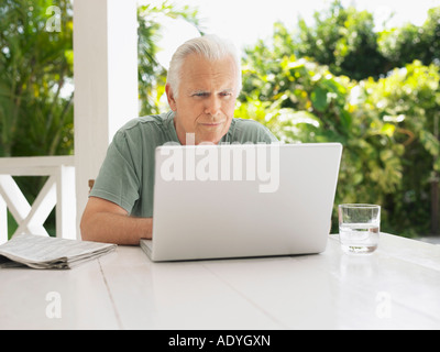 Man using laptop at verandah table Stock Photo