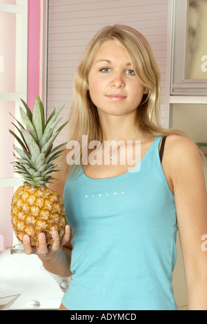 young blonde woman holding pineapple in her hand. Stock Photo