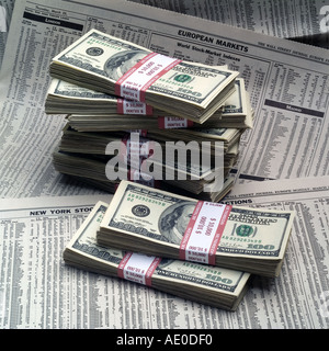 STACKS OF ONE HUNDRED DOLLAR BILLS ON FINANCIAL SECTION OF NEWSPAPERS Stock Photo