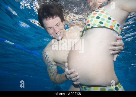 Pregnant Couple Swimming in Pool Couple therapy Stock Photo