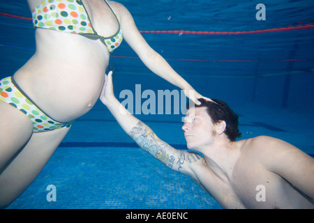 Pregnant Couple Swimming in Pool Couple therapy Stock Photo