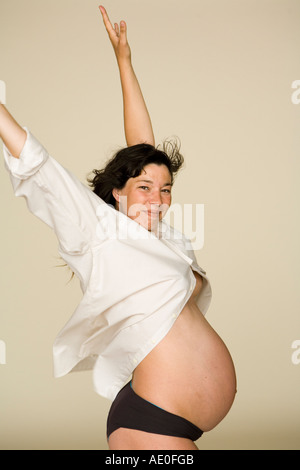 Pregnant Woman in White Shirt against white background wind blows her hair and shirt Stock Photo