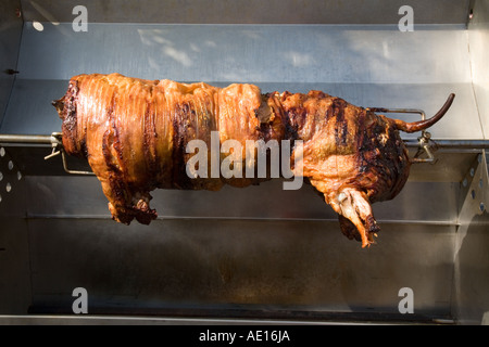 Rotating whole pig on a spit being cooked Stock Photo