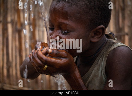 SIERRA LEONE West Africa Child cupping his hands together drinking well water Stock Photo